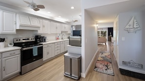Cocina moderna con armarios blancos, electrodomésticos de acero inoxidable y piso de madera.