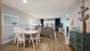 Una sala de estar moderna con comedor, un sofá, un televisor y vista a la playa.