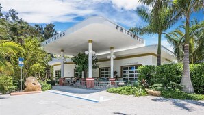 Un hotel con una fachada distintiva en blanco y dorado, un acceso cubierto y un letrero que dice "WHITNEY'S".