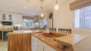 A spacious kitchen with wooden cabinetry, a central island, and pendant lighting. - My Island Escape (Santiago del Teide)