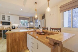 A spacious kitchen with wooden cabinetry, a central island, and pendant lighting. - My Island Escape (Santiago del Teide)