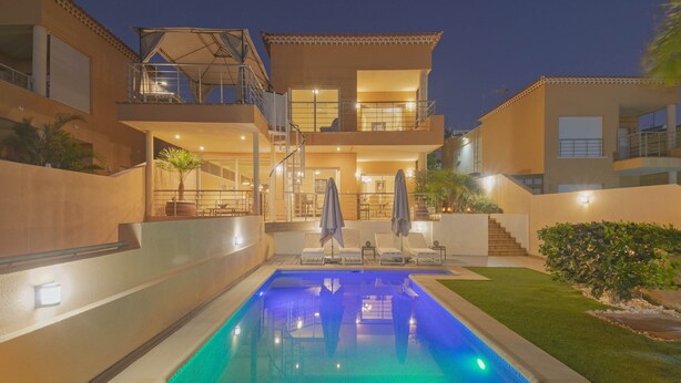 A modern two-story house with a swimming pool, outdoor seating, and a well-lit patio area. - My Island Escape (Santiago del Teide)