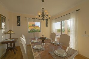 A dining room with a wooden table set for four, a chandelier, and a view of the outdoors. - My Island Escape (Santiago del Teide)