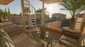 A rooftop terrace with a glass table, two chairs, a palm tree, and a potted plant. - My Island Escape (Santiago del Teide)