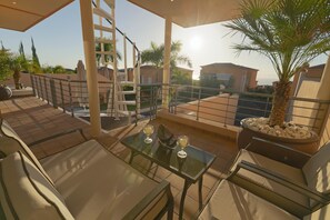 A rooftop terrace with a glass table, two chairs, a palm tree, and a potted plant. - My Island Escape (Santiago del Teide)