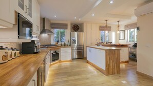 A modern kitchen with wooden countertops, stainless steel appliances, and a central island. - My Island Escape (Santiago del Teide)
