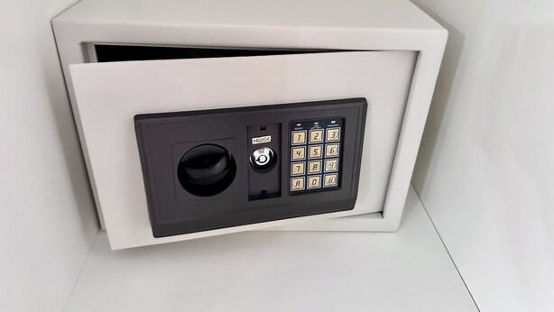 Een witte kluis met een keypad en een cijferslot.