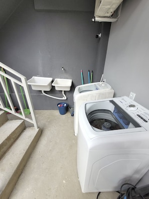 A laundry room with a washing machine, two sinks, and a blue bucket. - Hotel Manaus - Dom Pedro (Manaus)