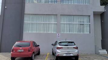A parking area with two cars parked in front of a building with large windows and a sign indicating a private parking area.