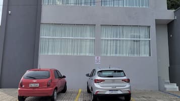 Uma área de estacionamento com dois carros estacionados em frente a um edifício de grandes janelas e uma placa indicando estacionamento privado.