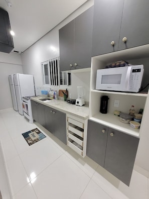 A modern kitchen with grey cabinets, a white countertop, a microwave, a blender, and a coffee maker. - Hotel Manaus - Dom Pedro (Manaus)