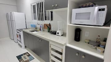 Una cocina moderna con armarios grises, encimera blanca, microondas integrado y cafetera.