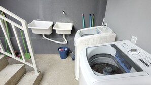 A laundry room with a washing machine, two sinks, and a blue bucket. - Hotel Manaus - Dom Pedro (Manaus)