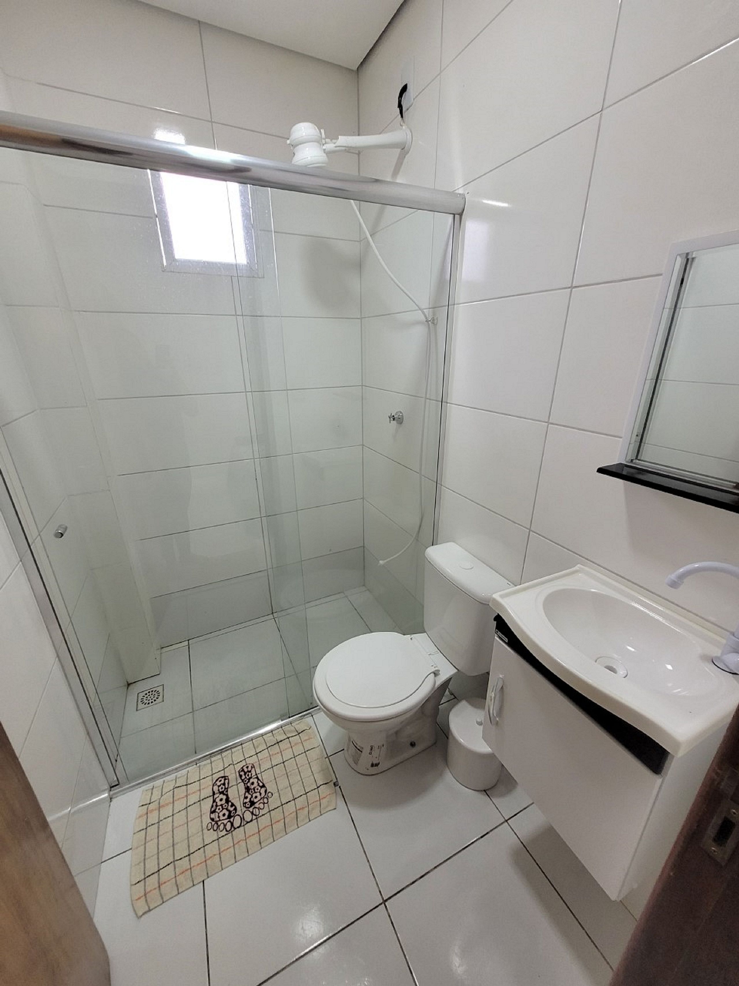 Un baño con ducha acristalada, inodoro y lavamanos con espejo.