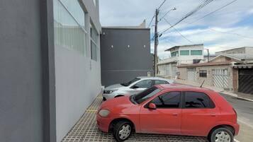 A parking area with a red car parked in front of a building with large windows.