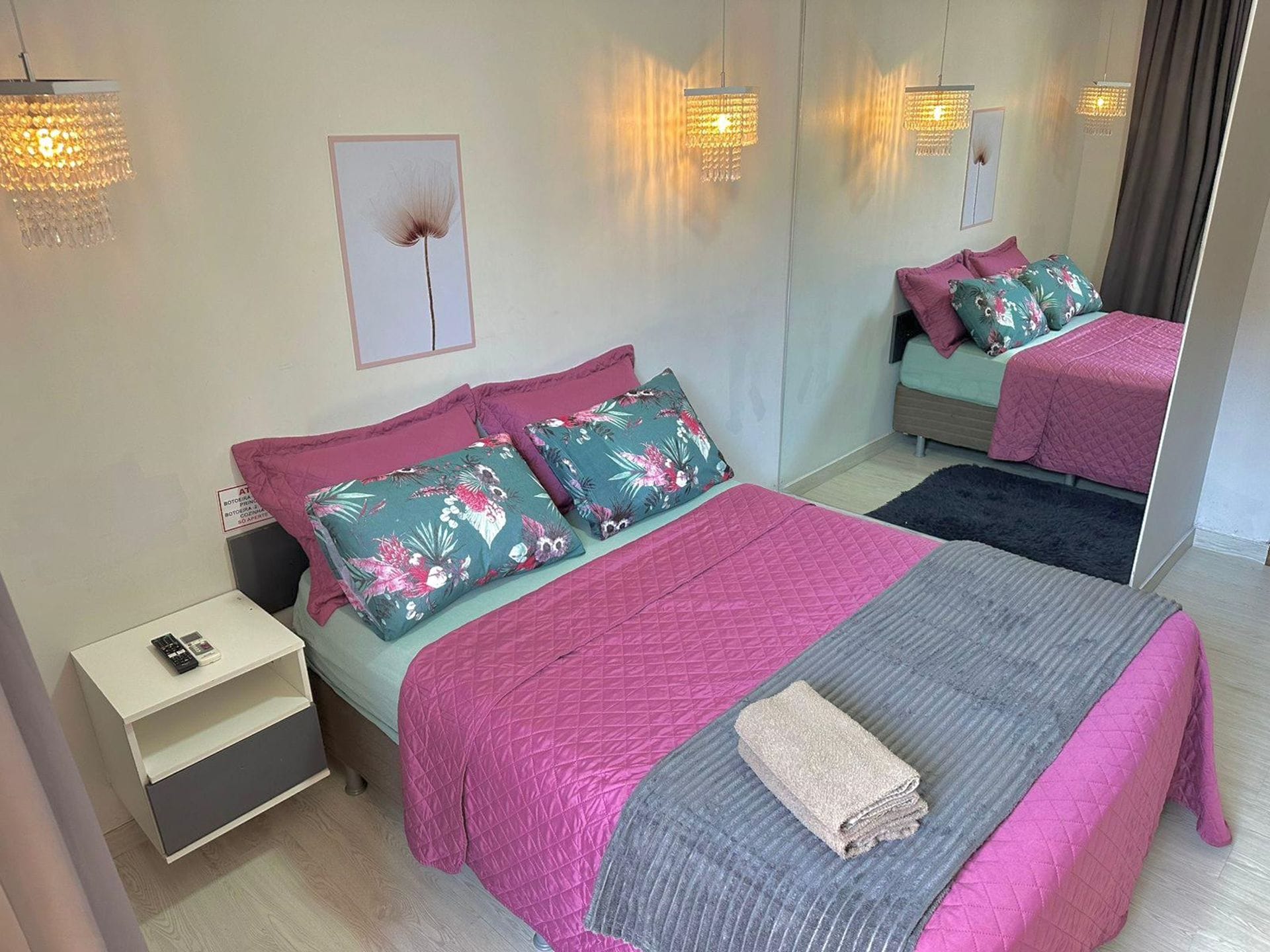 A modern bedroom with a bed, bedside tables, a mirror, and decorative pillows.