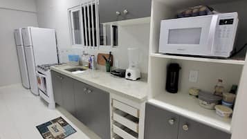 A modern kitchen with grey cabinets, a white countertop, a microwave, and a coffee maker.