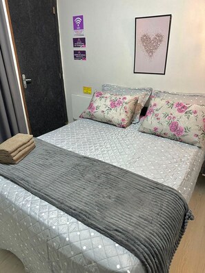 A neatly made bed with a grey quilt, two floral pillows, and a grey throw blanket. - Hotel Manaus - Dom Pedro (Manaus)