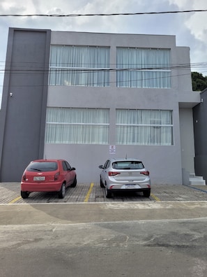 A parking area with two cars parked in front of a building with large windows and a sign indicating a reserved parking space. - Hotel Manaus - Dom Pedro (Manaus)