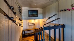 A wooden interior with skis and snowboards on racks, a welcome sign, and a painting of a mountain. - Der Kastle Ski Condo · Schweitzer Retreat Comfort for all Prime location (Sandpoint)