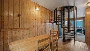 A wooden interior with a dining table and chairs, a spiral staircase, and a view of the outside. - Der Kastle Ski Condo · Schweitzer Retreat Comfort for all Prime location (Sandpoint)