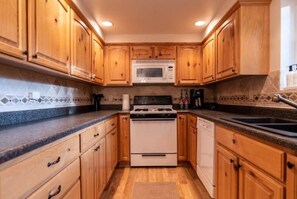 Kitchen features a central stove, microwave, and sink, with ample countertop space.