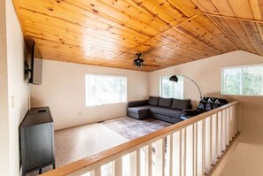 Cozy living space with a sloped ceiling, sectional sofa, and flat-screen TV.