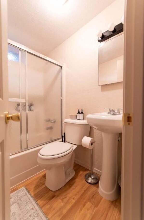 Bathroom features a glass-enclosed shower, pedestal sink, and toilet.