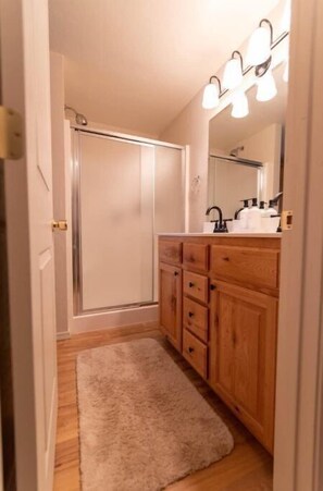 Bathroom features a vanity with multiple drawers and a large mirror above, a sink, and a shower.