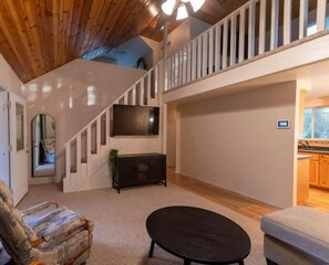 Relax in a spacious living area with a high ceiling, featuring a modern staircase and comfortable seating area.