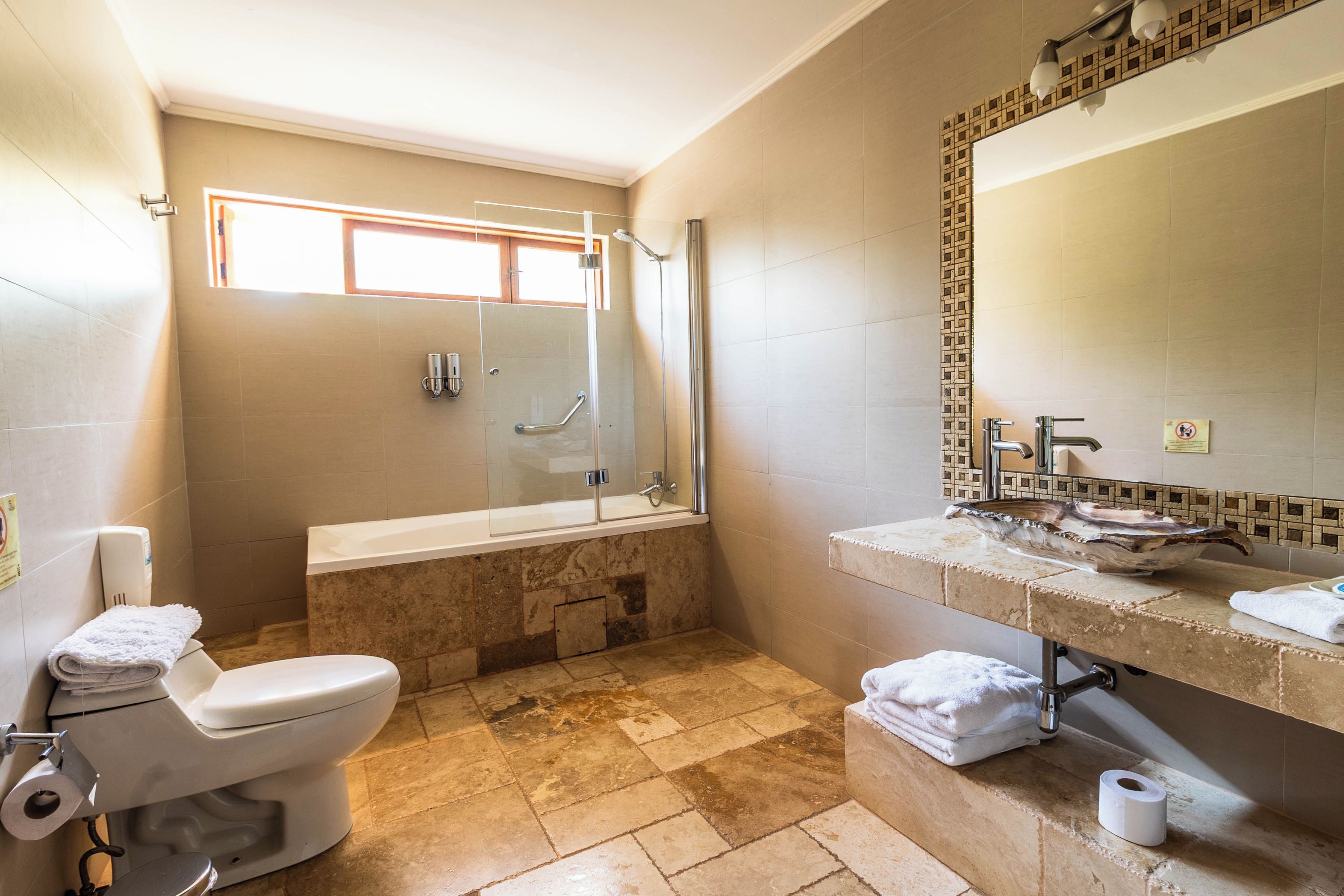 A bathroom with a toilet, a shower, a bathtub, and a sink with a mirror.