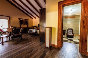 A room with wooden flooring, a dining table, chairs, a massage chair, and a wall-mounted clock.