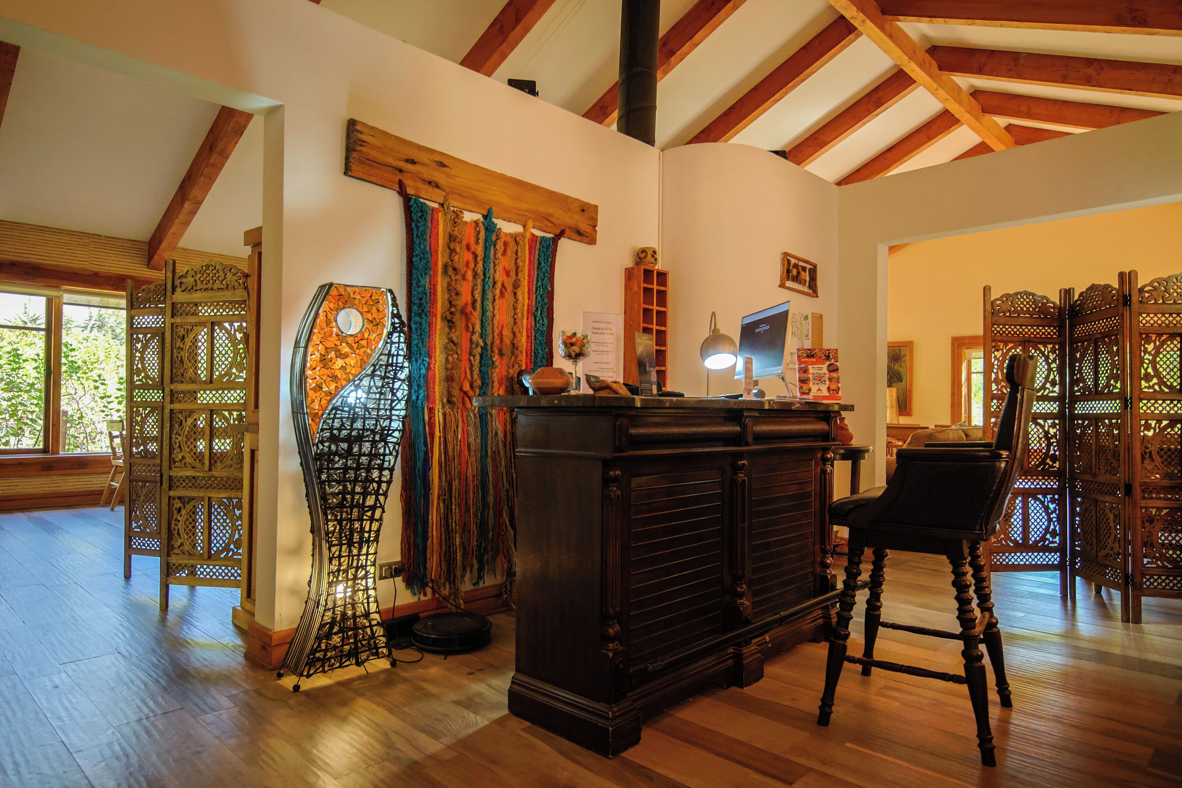 A room with a wooden ceiling, a bar area with stools, and a large window with a view of greenery.