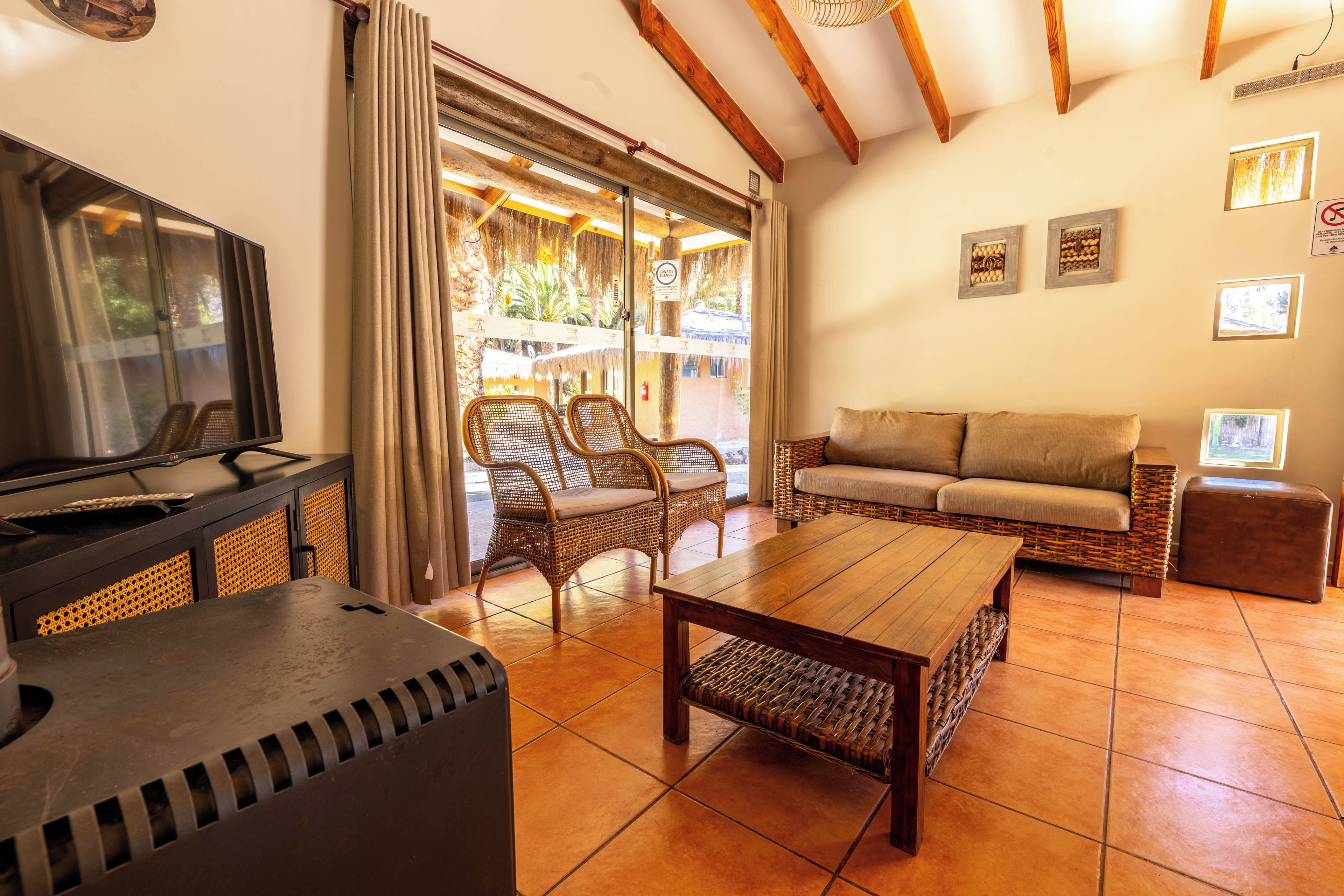 A living room with a TV, wicker furniture, a sofa, and a table.
