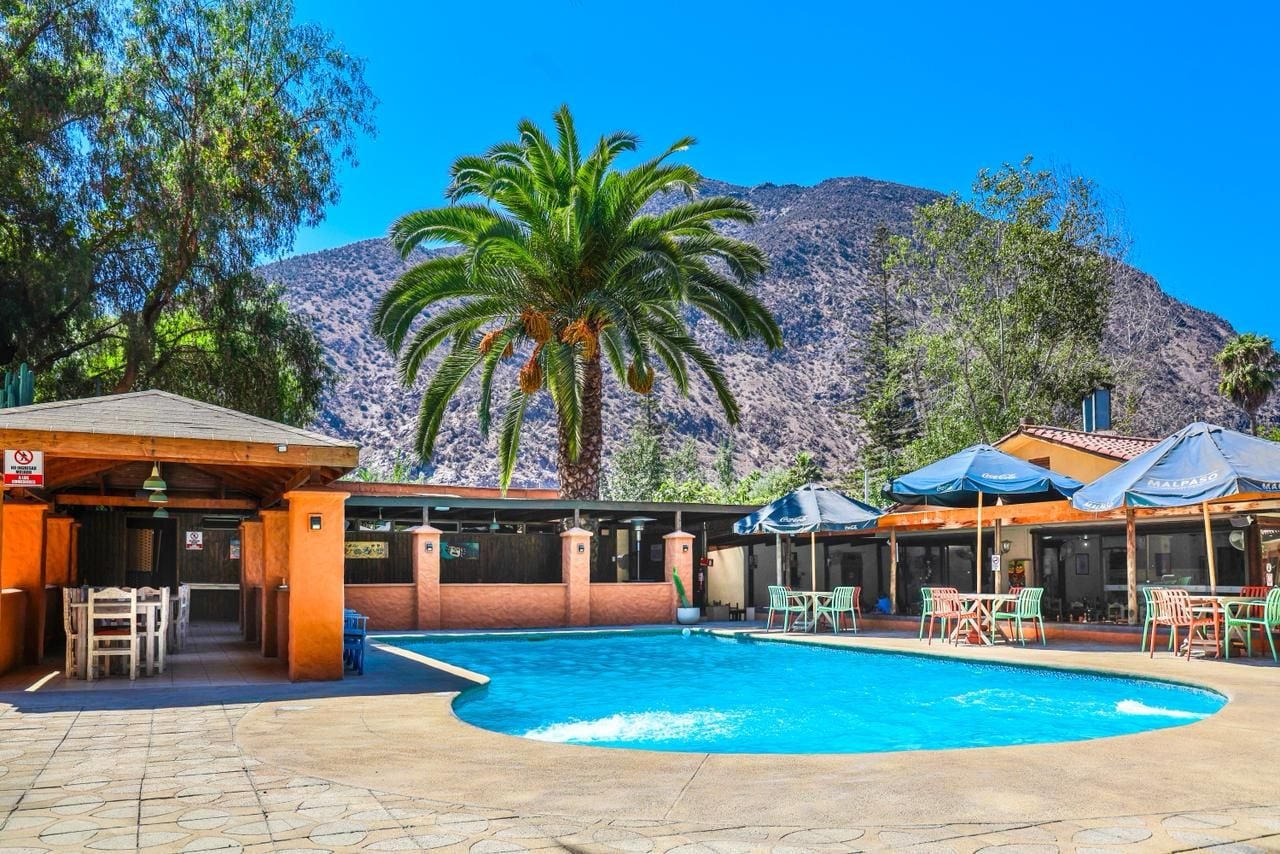 A pool area with a mountain backdrop, outdoor seating, and a covered patio.
