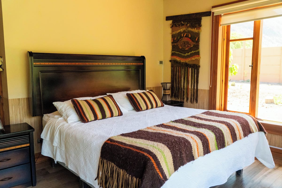 A bed with a striped blanket, a wooden headboard, and a nightstand with a lamp.
