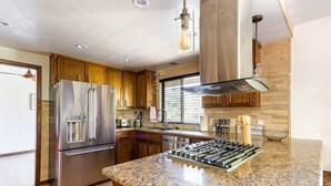 Eine moderne Küche mit Edelstahlgeräten, Holzschränken und einer Arbeitsplatte aus Granit.