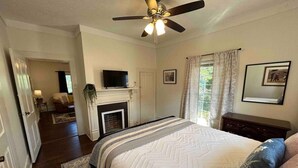 Une chambre à coucher avec un lit, un ventilateur de plafond, une cheminée et un téléviseur.