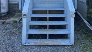 A house with a front porch, a set of stairs leading to a double door with glass panels, and a small window above the door. - Eddies Place LLC (Berkeley Springs)