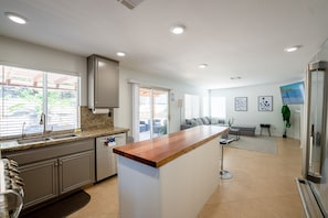 A modern kitchen with granite countertops, a wooden island, and a built-in oven. - Luxe Resort Style Home Stunning 8 Beds with Pool (El Cajon)