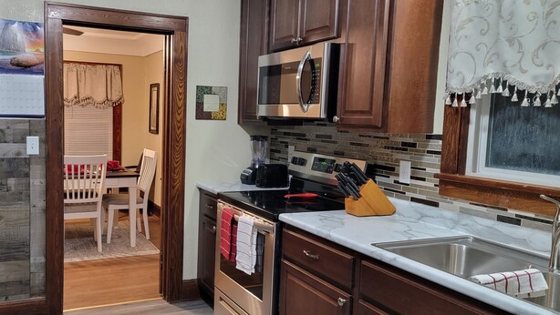 A kitchen with wooden cabinets, a stainless steel microwave, a stove, and a sink. -  Oak Street Retreat  (Menasha)