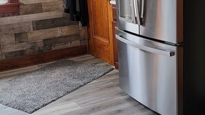 A kitchen with a stainless steel refrigerator, wooden flooring, and a wooden door. -  Oak Street Retreat  (Menasha)