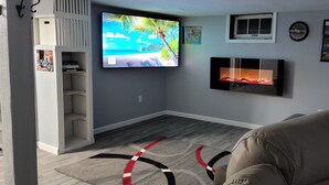A living room with a flat-screen TV, a fireplace, a sofa, and a wall-mounted shelf. -  Oak Street Retreat  (Menasha)