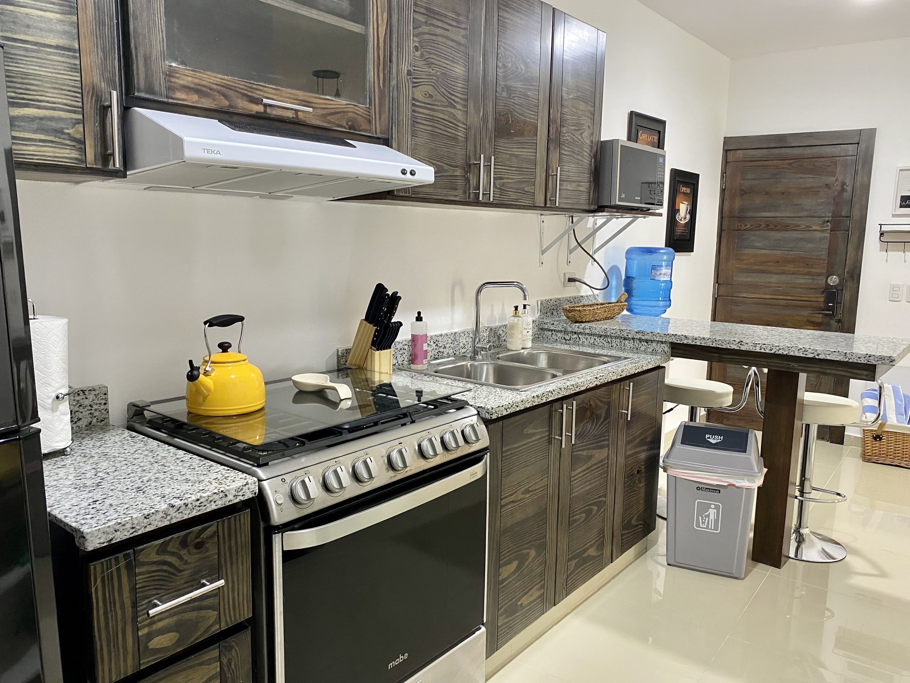 A modern kitchen with a stove, sink, and wooden cabinets.