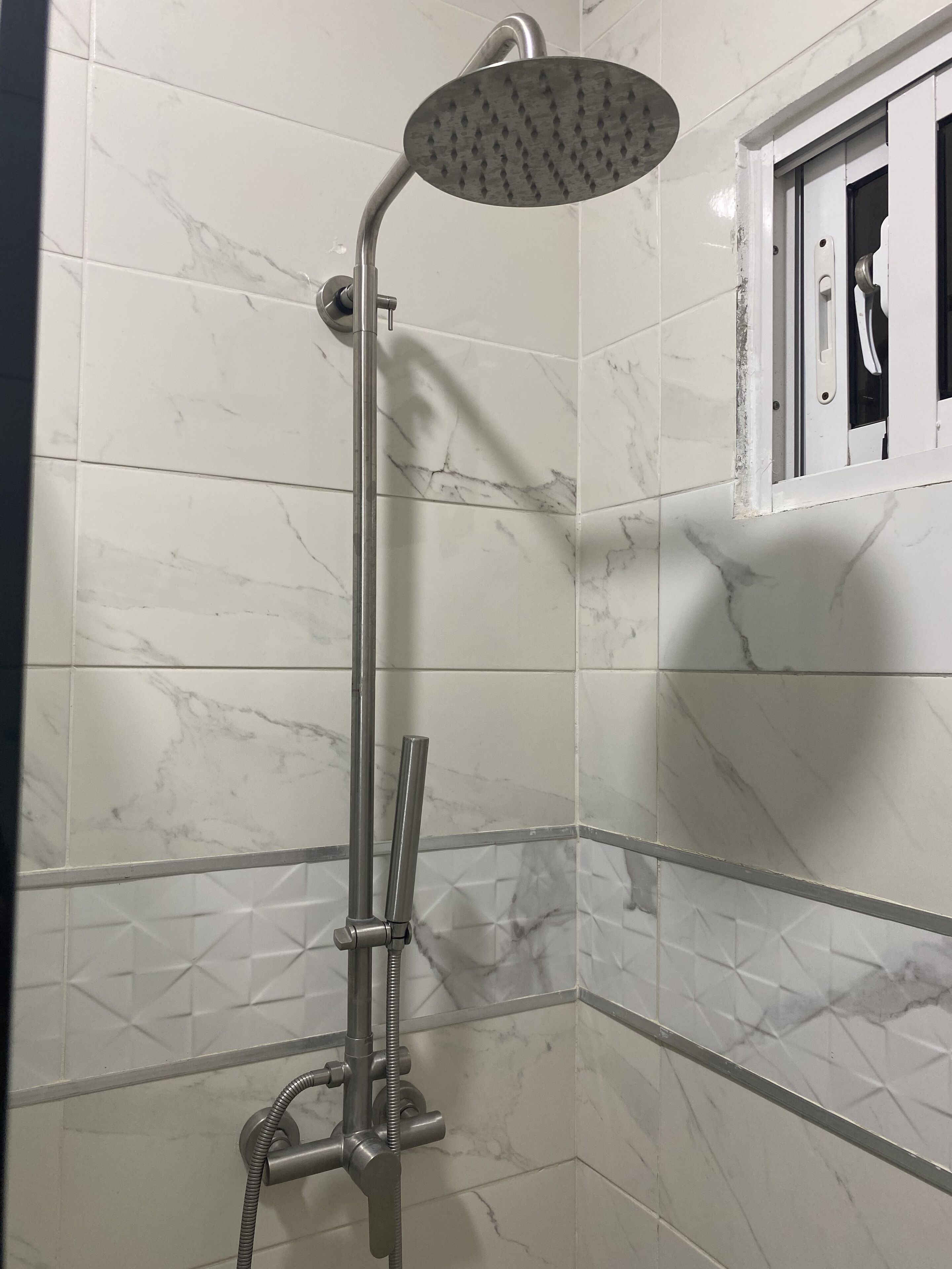 A shower with a handheld showerhead and a handheld hose.
