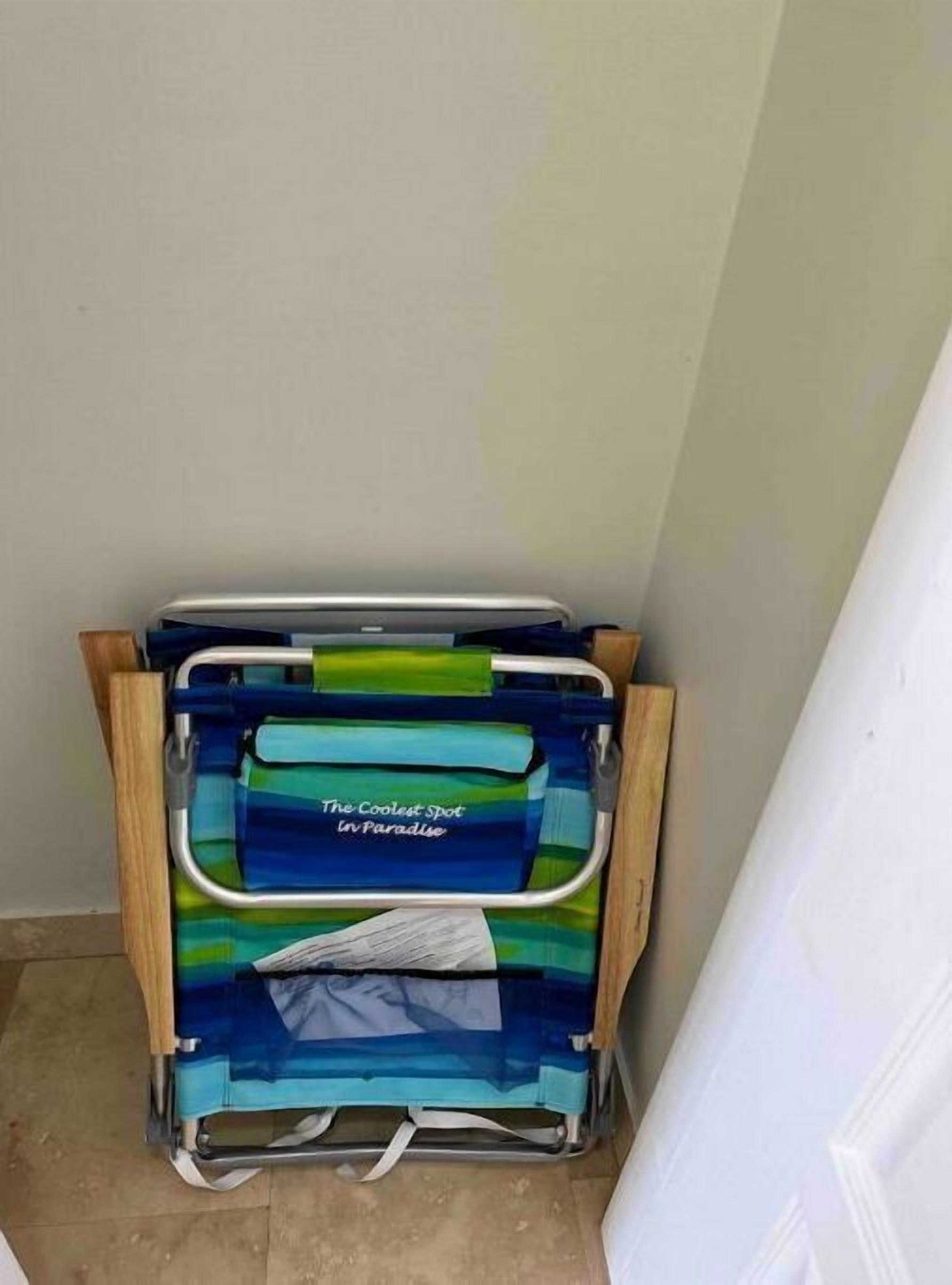 A corner of a room with a blue and green striped chair and a wooden cabinet.