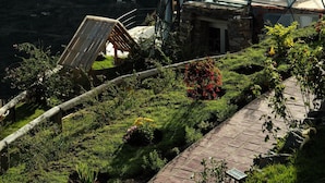 Una estructura de domo geodésico sobre una base de piedra, rodeada por un jardín exuberante y un acantilado escarpado.