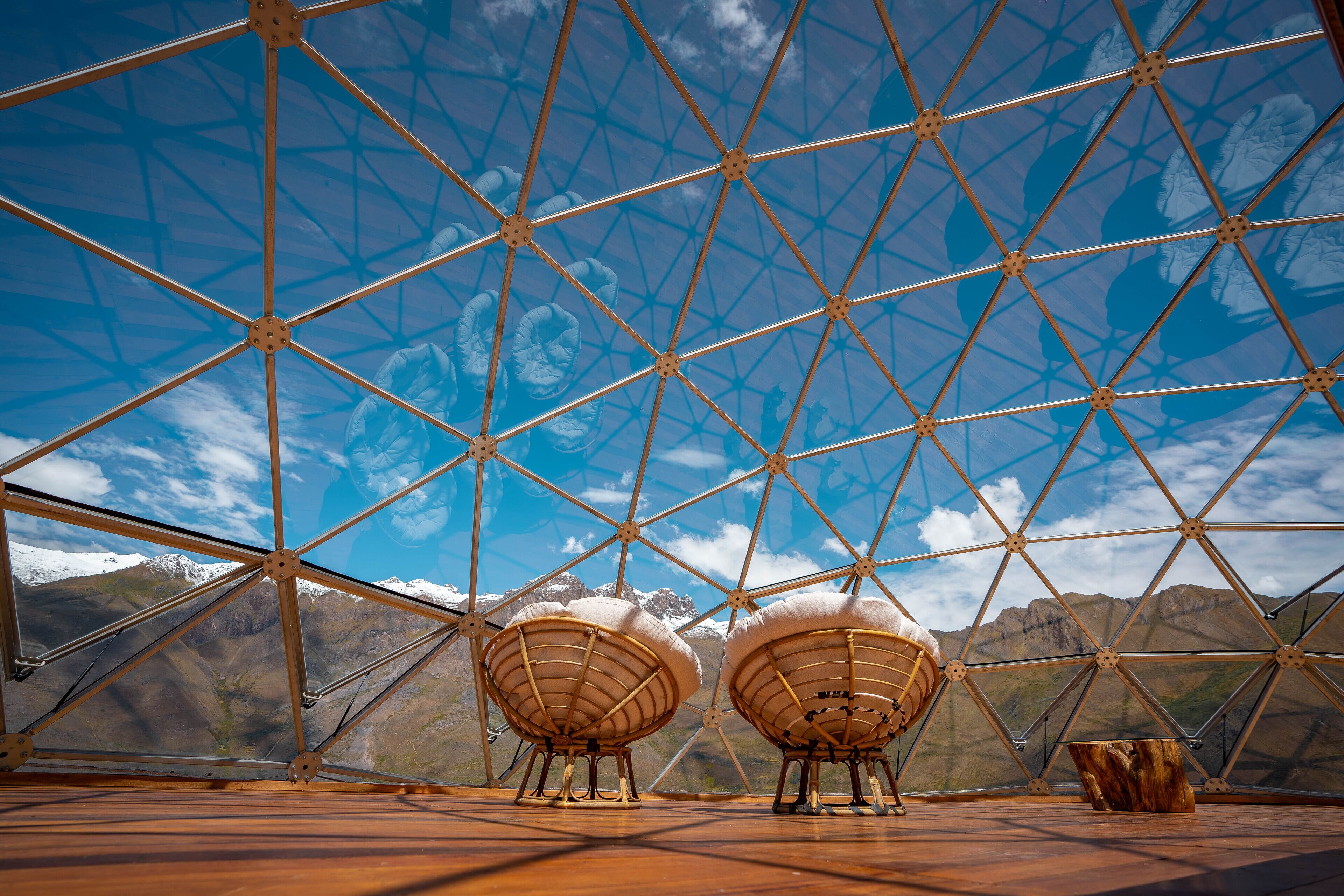A geodesic dome structure with a clear view of a mountainous landscape through its transparent sections.