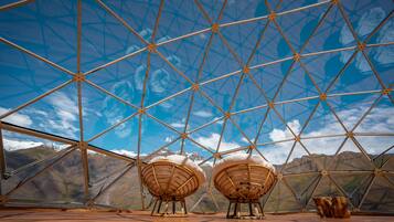 A geodesic dome structure with a clear view of a mountainous landscape through its transparent sections.