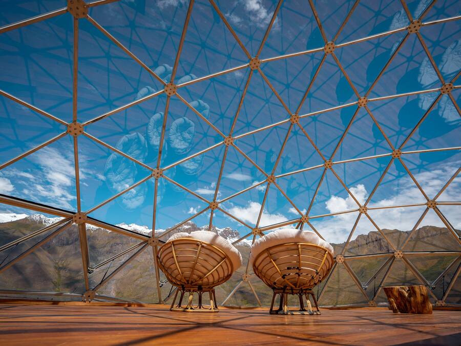 A geodesic dome structure with a clear view of a mountainous landscape through its transparent sections.